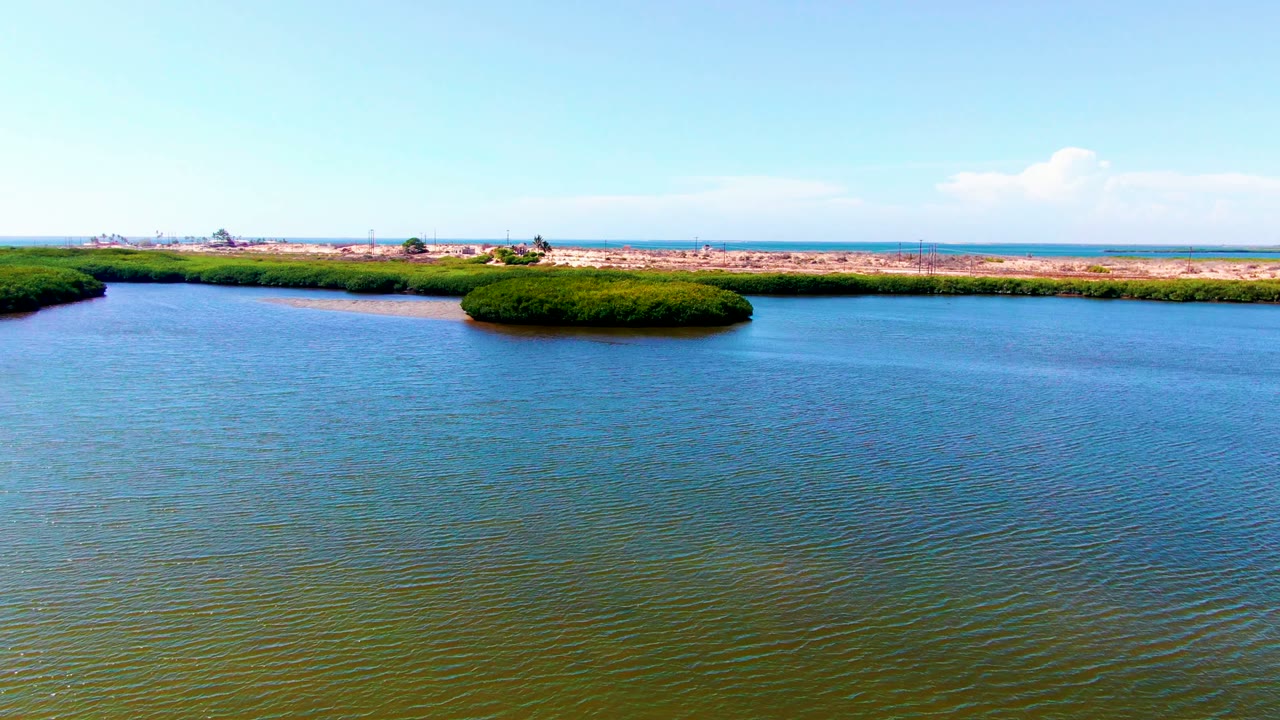 Wide aerial waterway view with low green islands and a dry shore behind them.