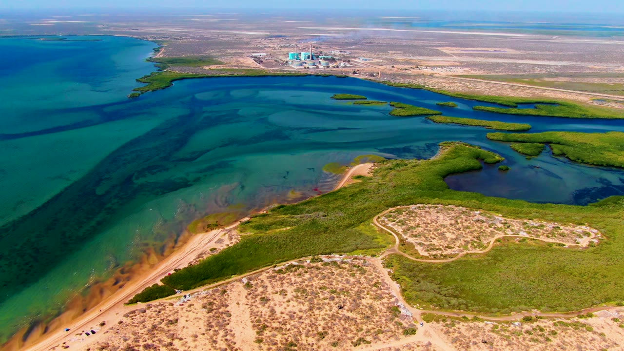 At 0:02 the San Carlos lagoon remains centered, with brighter turquoise water on the left, marsh strips on the right, dune paths below, and no visible people.