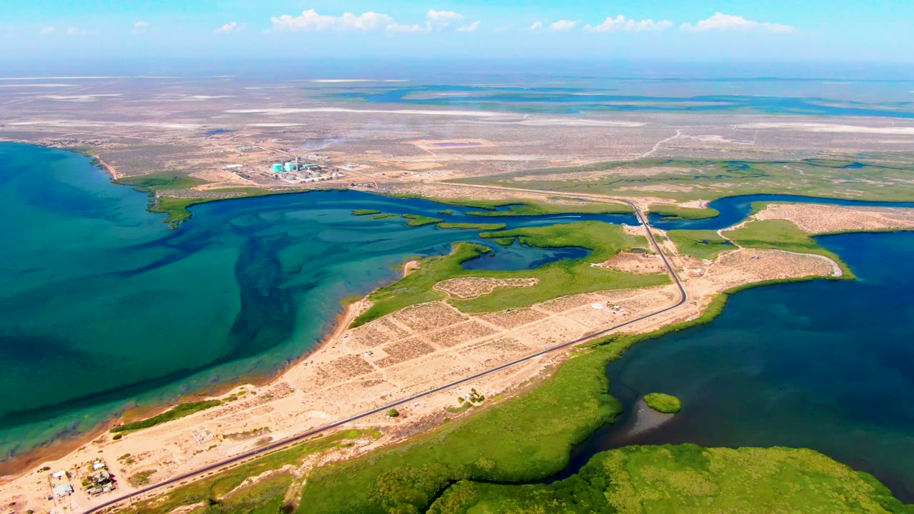 Aerial coastal wetland with road crossing between blue water areas.