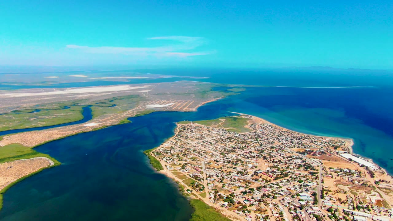 Aerial shoreline view with town foreground and open ocean beyond.