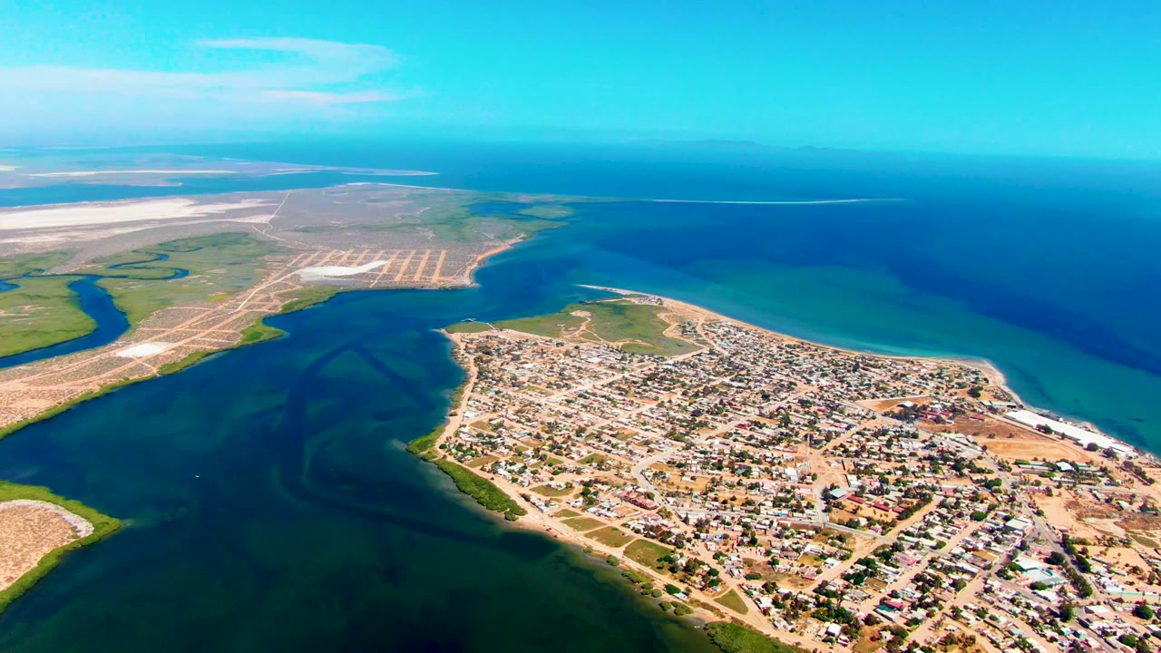 Aerial coastal landscape with town, tidal inlet, beach, and pale land flats.