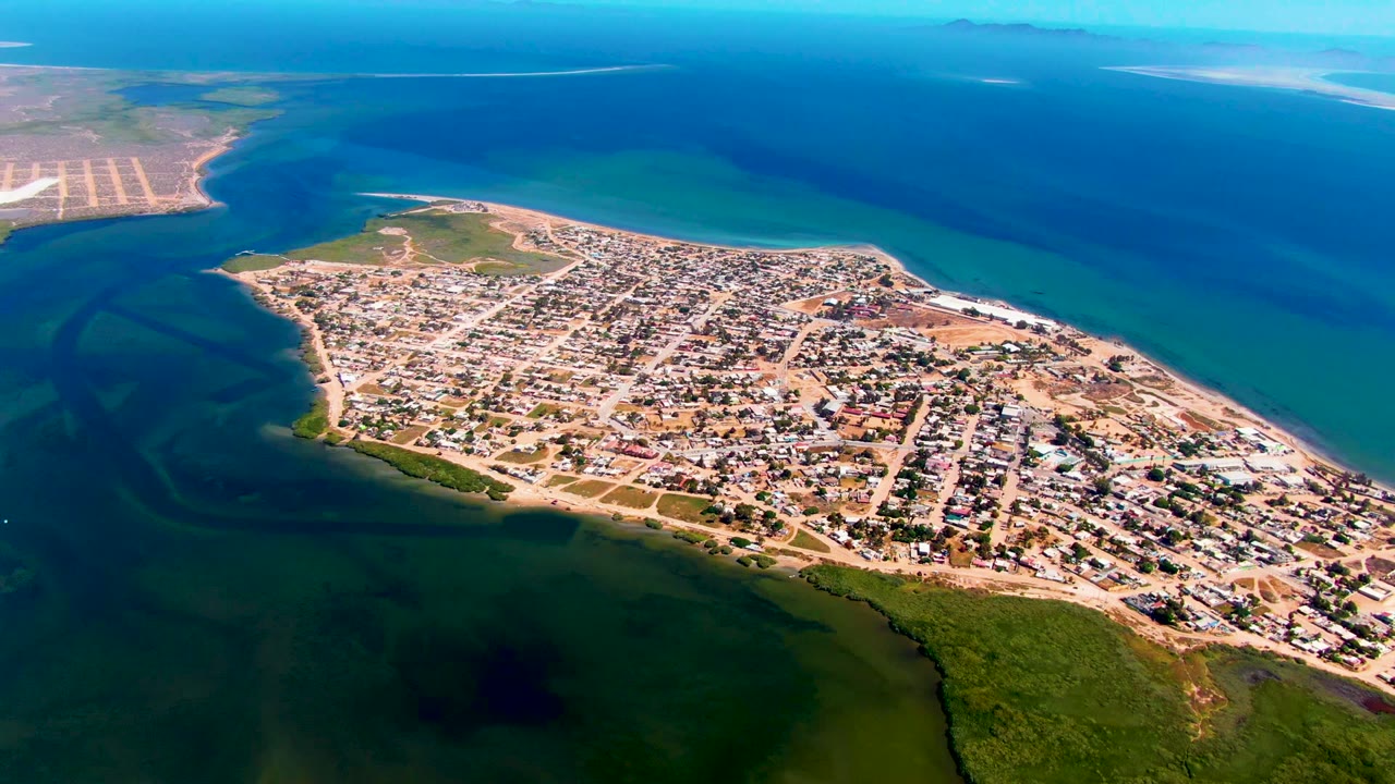 Wide drone view of a peninsula town with gridded streets and water on both sides.