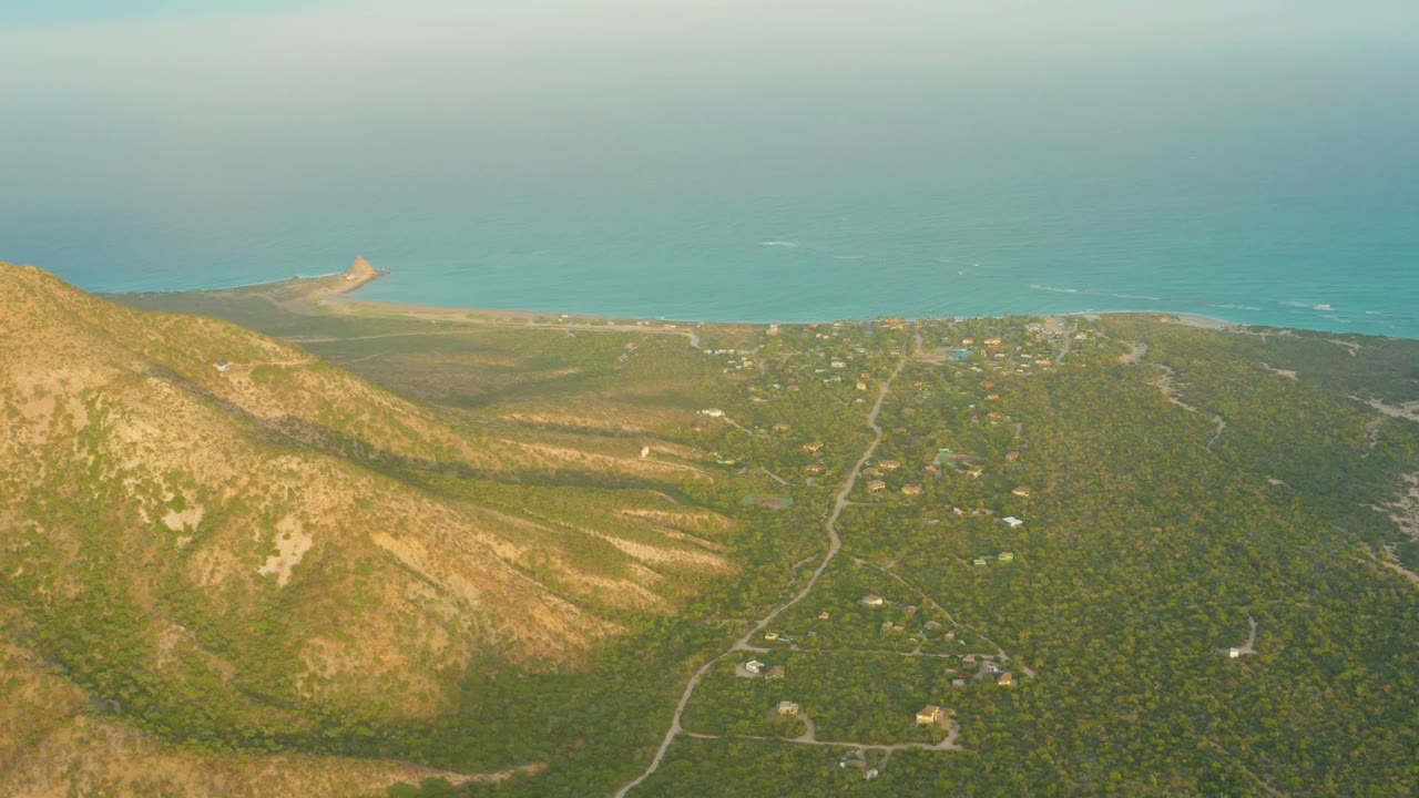 Sunlit hillside above green coastal terrain and ocean.