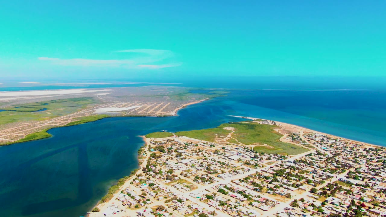 Third frame keeps San Carlos coastline in a broad aerial composition, with residential blocks at the lower right and the field grid across the left shore, no visible people.