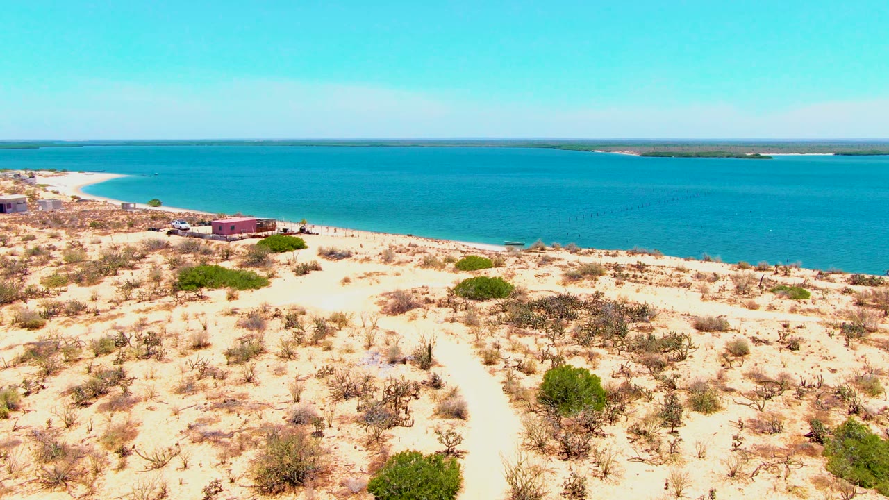 Beachside buildings near a sandy path and blue water