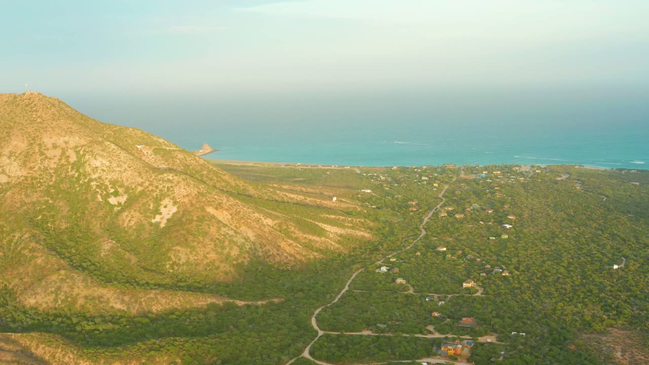 Third frame shows Cabo Pulmo's rocky hillside at left, a forested valley with pale roads and small buildings below, and the blue sea stretching across the upper background, with no visible people.