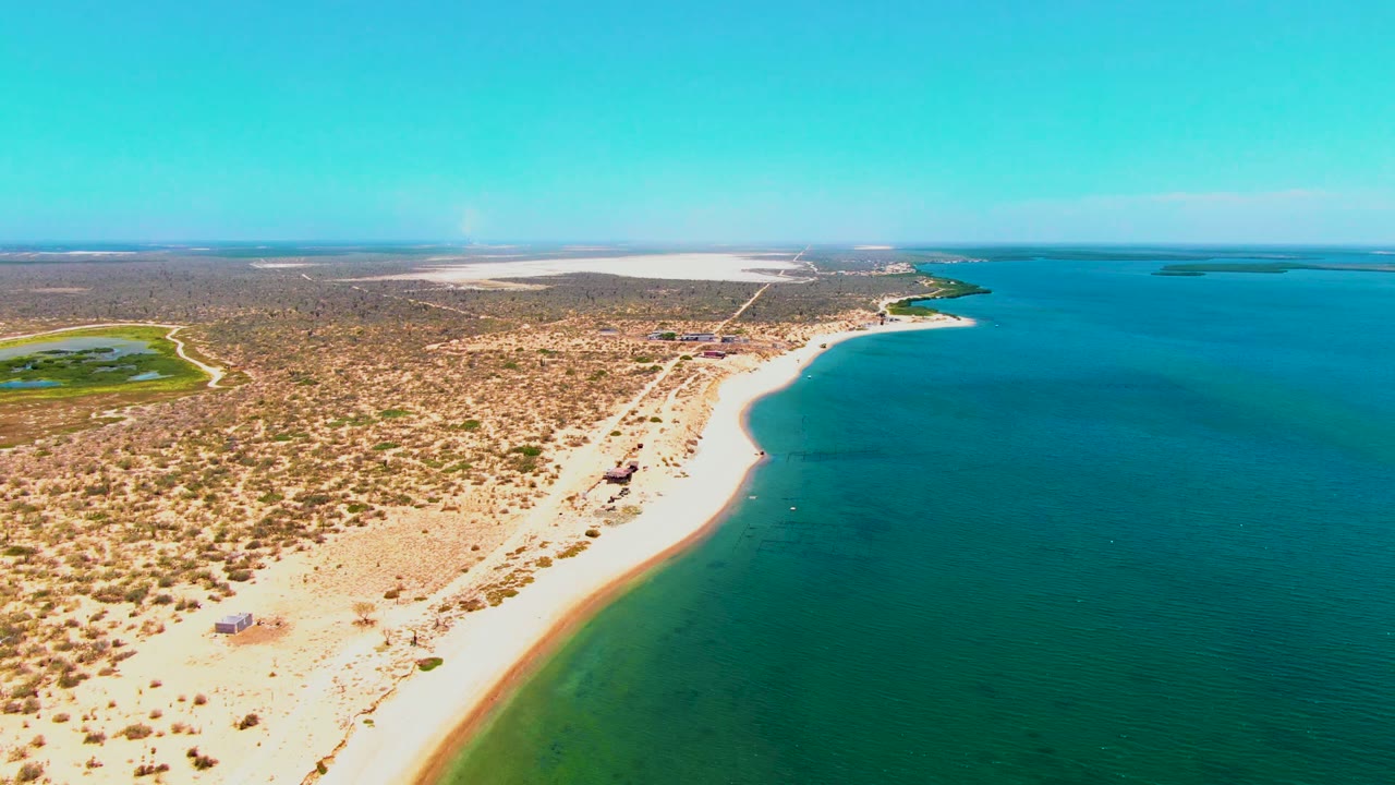 Two-second frame from San Carlos, Baja California Sur, holding a broad drone view of sand, scrub, and open turquoise water with no visible people.