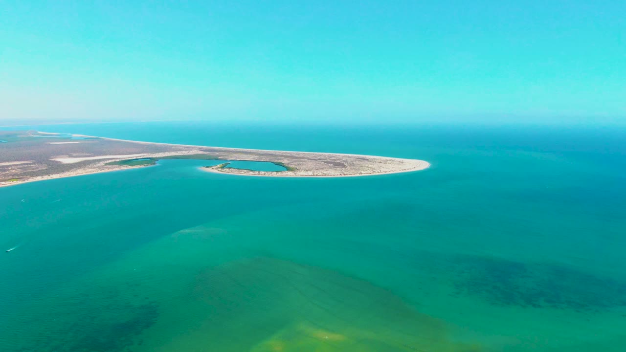 Sandy island and shallow turquoise water seen from above.
