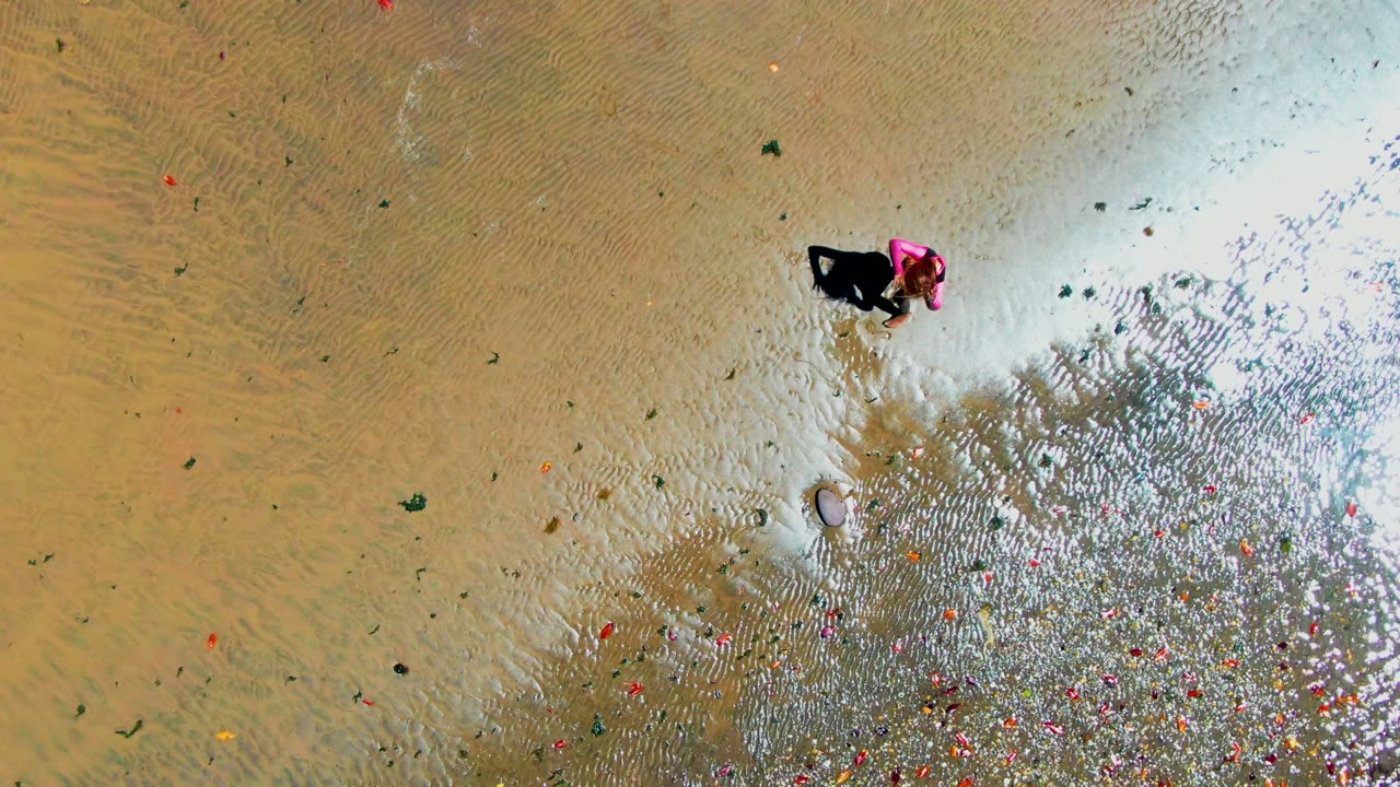 Person near the upper center of shallow water with ripples and scattered debris below.