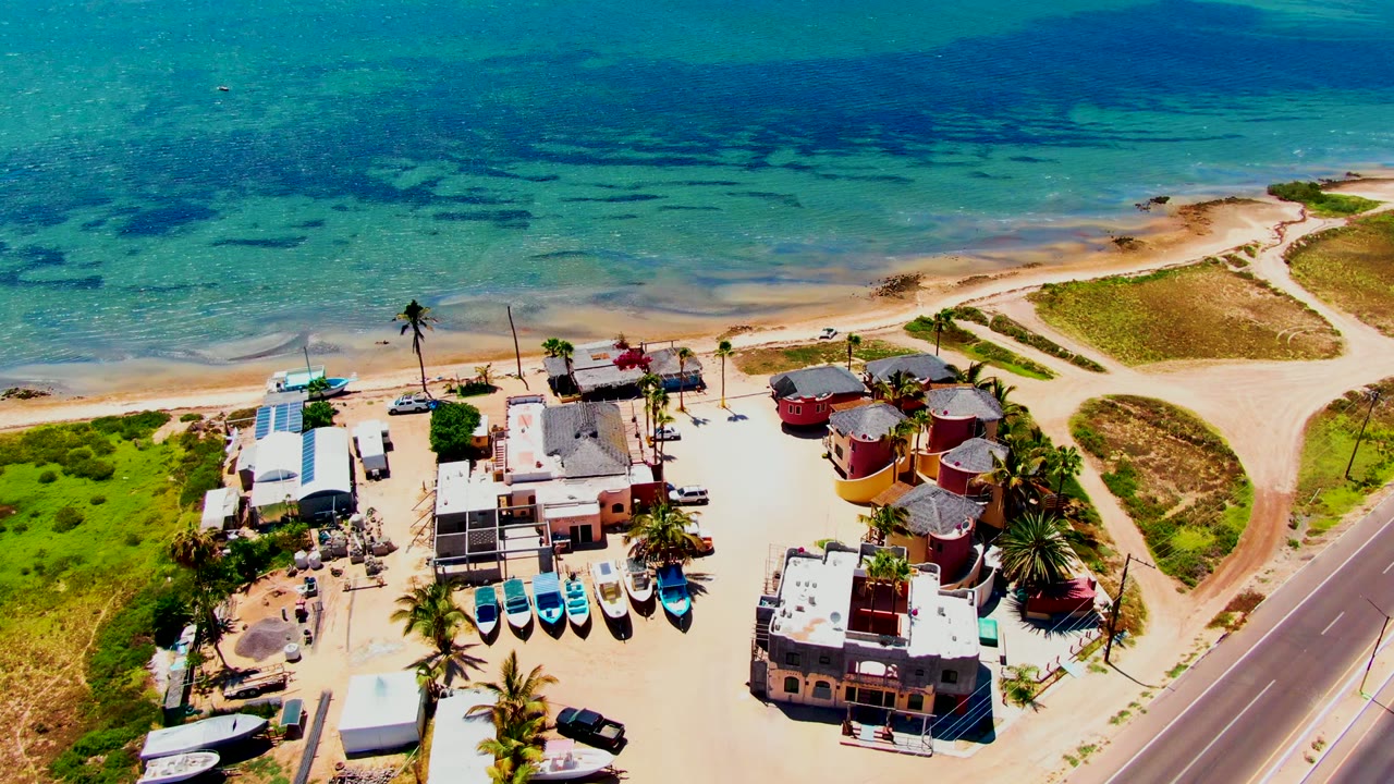 Elevated coastal view with boats lined near buildings and ocean behind.