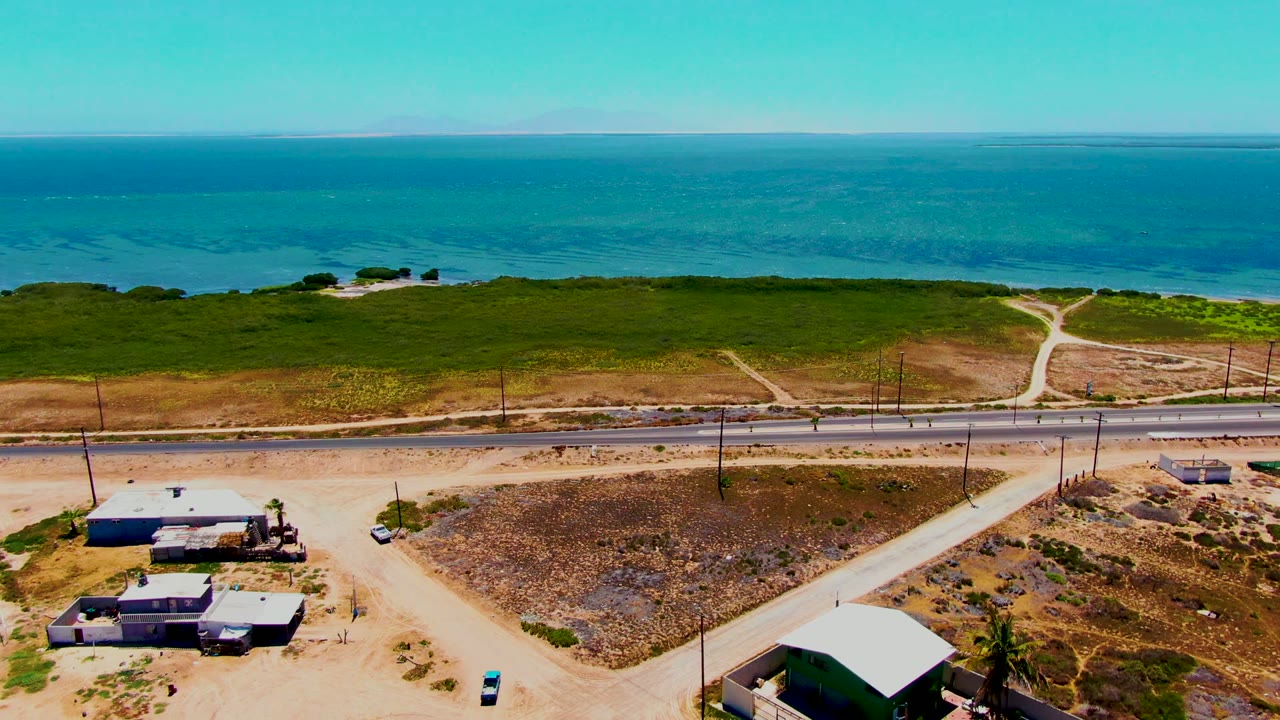 Coastal road beside green shoreline and blue water.
