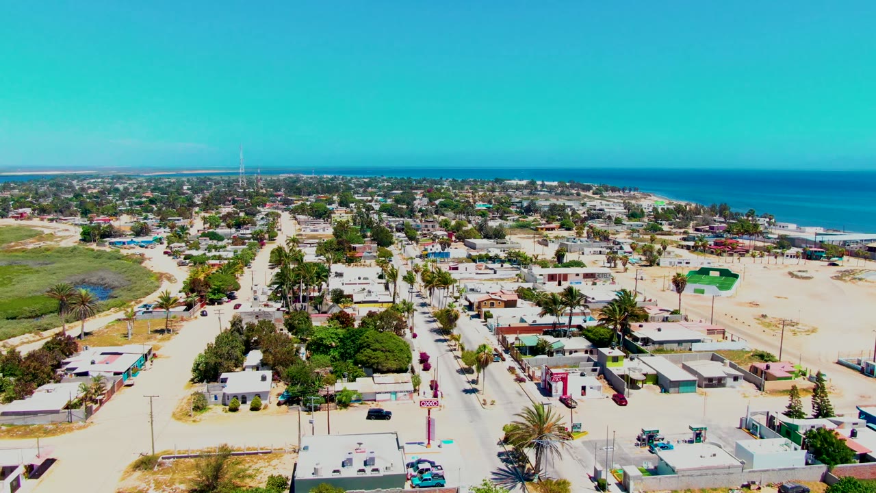 Third frame shows San Carlos, Baja California Sur, from above with rooftops, palm-lined blocks, a pale sandy foreground, blue water beyond town, and no visible people.
