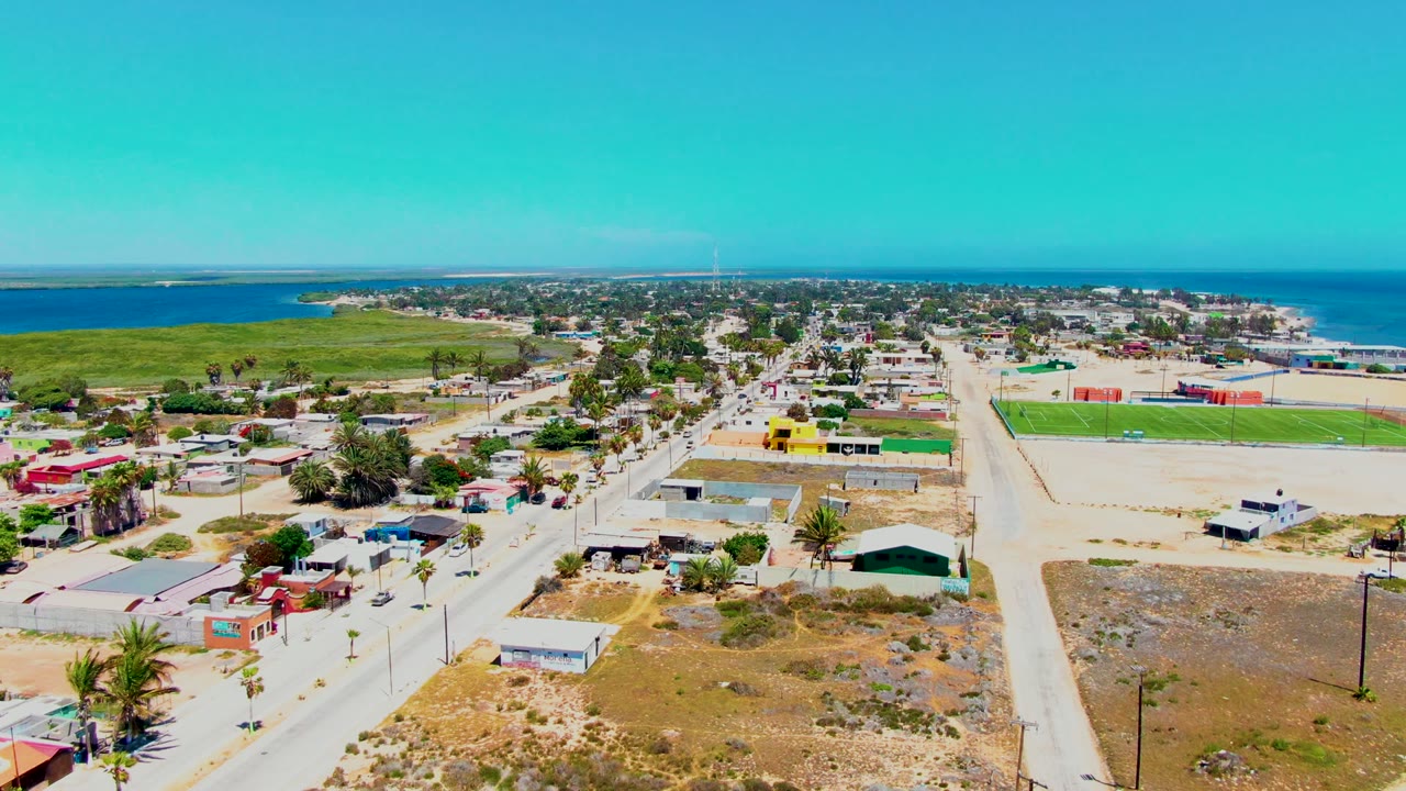High coastal town view with dry lots, homes, roads, and water in the distance
