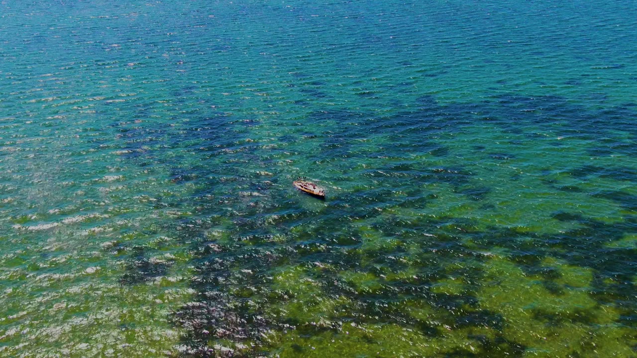 Small boat farther across clear blue-green ocean water.