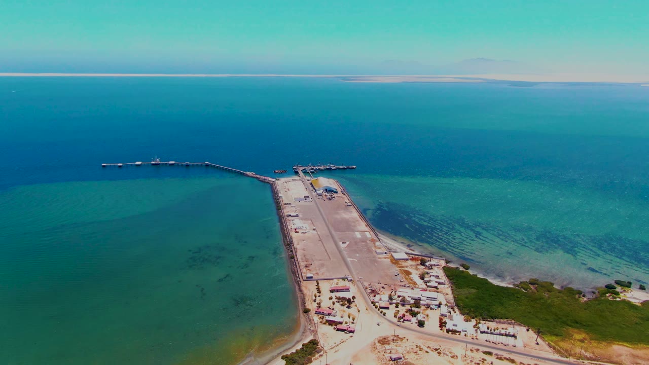 Aerial pier and jetty over clear blue-green coastal water.