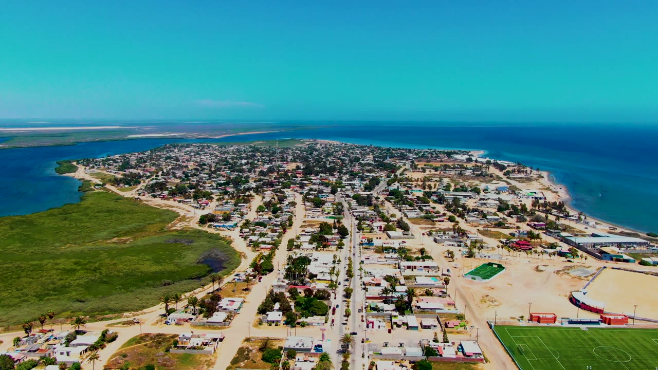 High aerial view of sandy streets, homes, marsh, lagoon, and ocean.