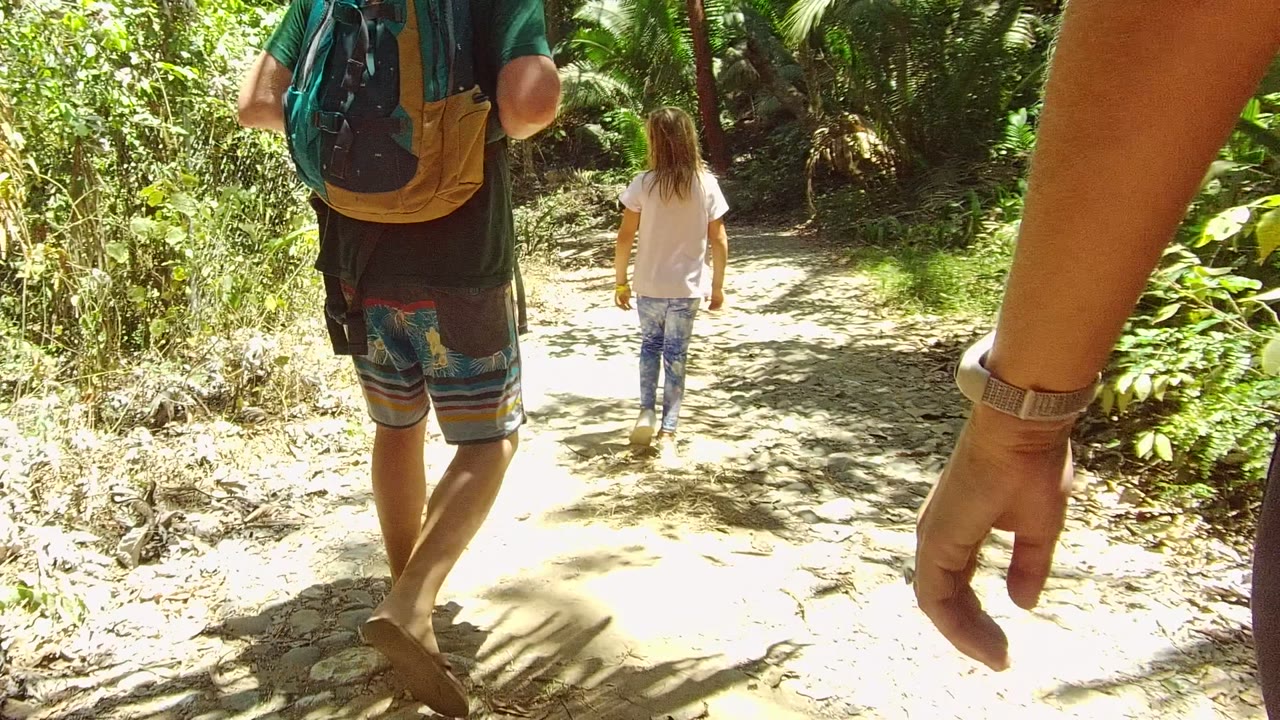 Backpack wearer and child farther along a bright dirt path