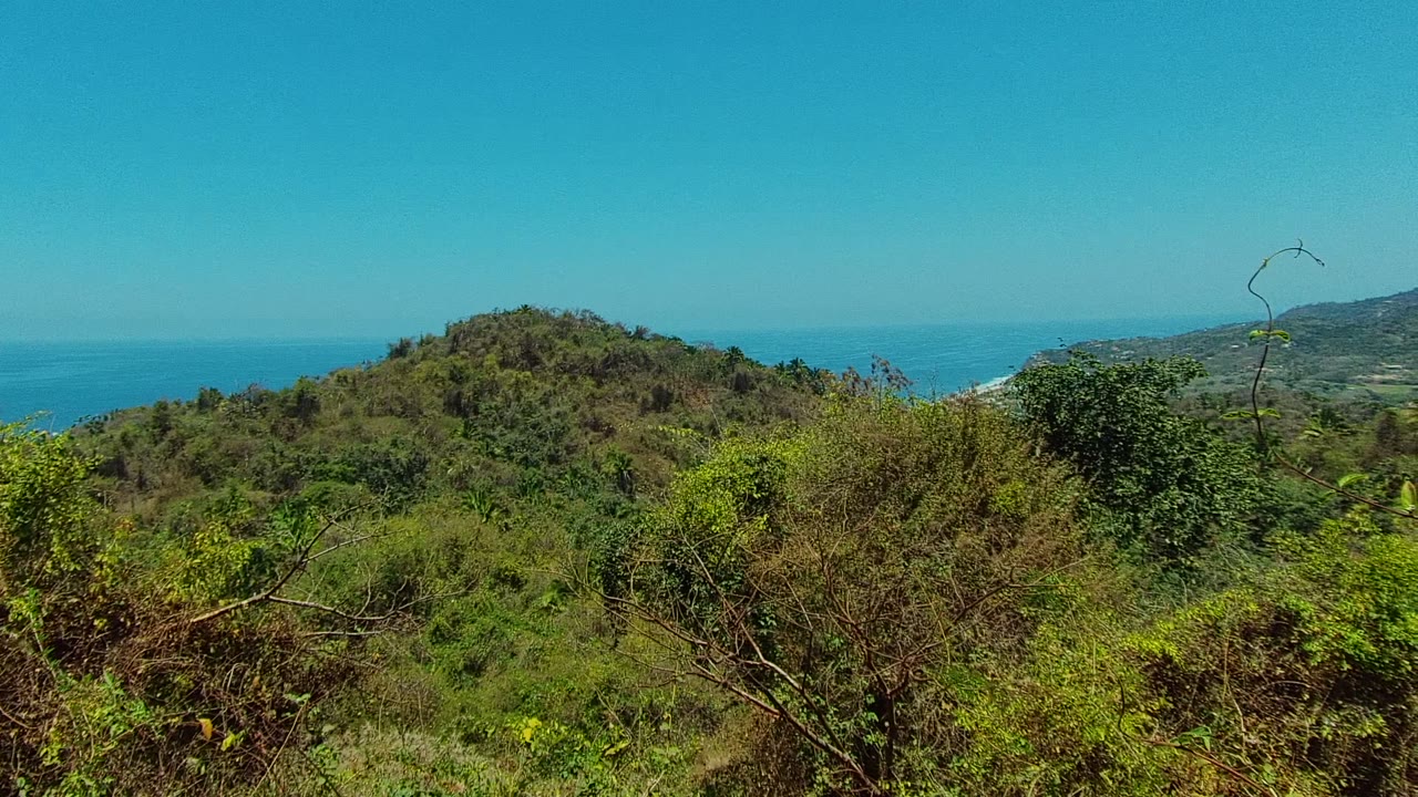 Green coastal hills with ocean visible behind them.