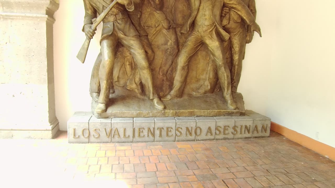 Bronze sculptural figures above the inscription LOS VALIENTES NO ASESINAN.