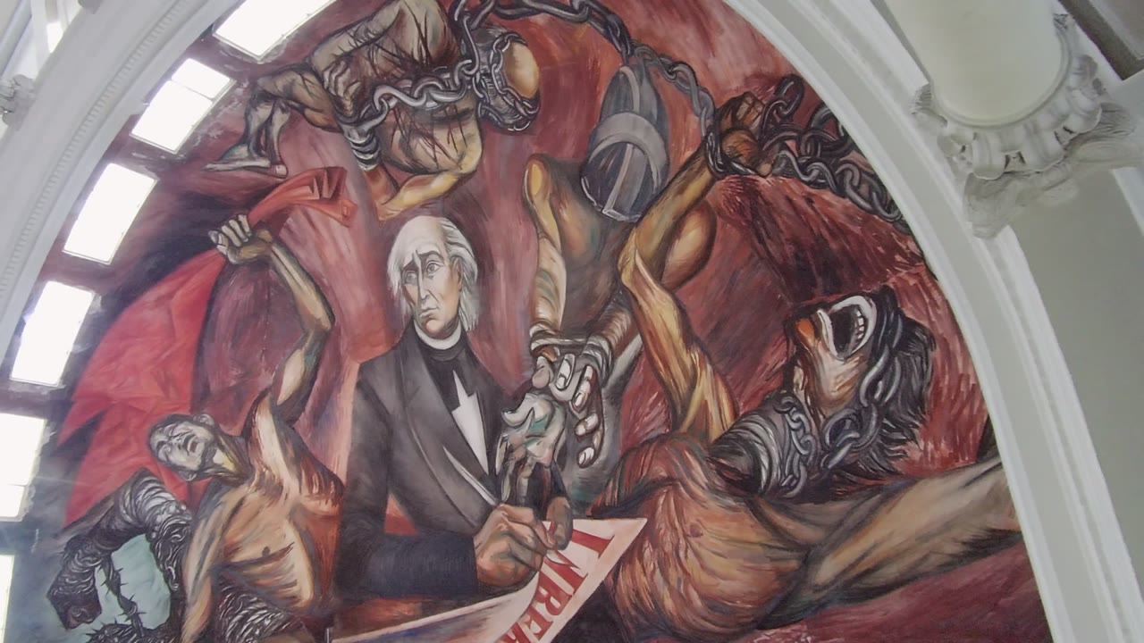Close view of mural figure writing with chained figures and window light