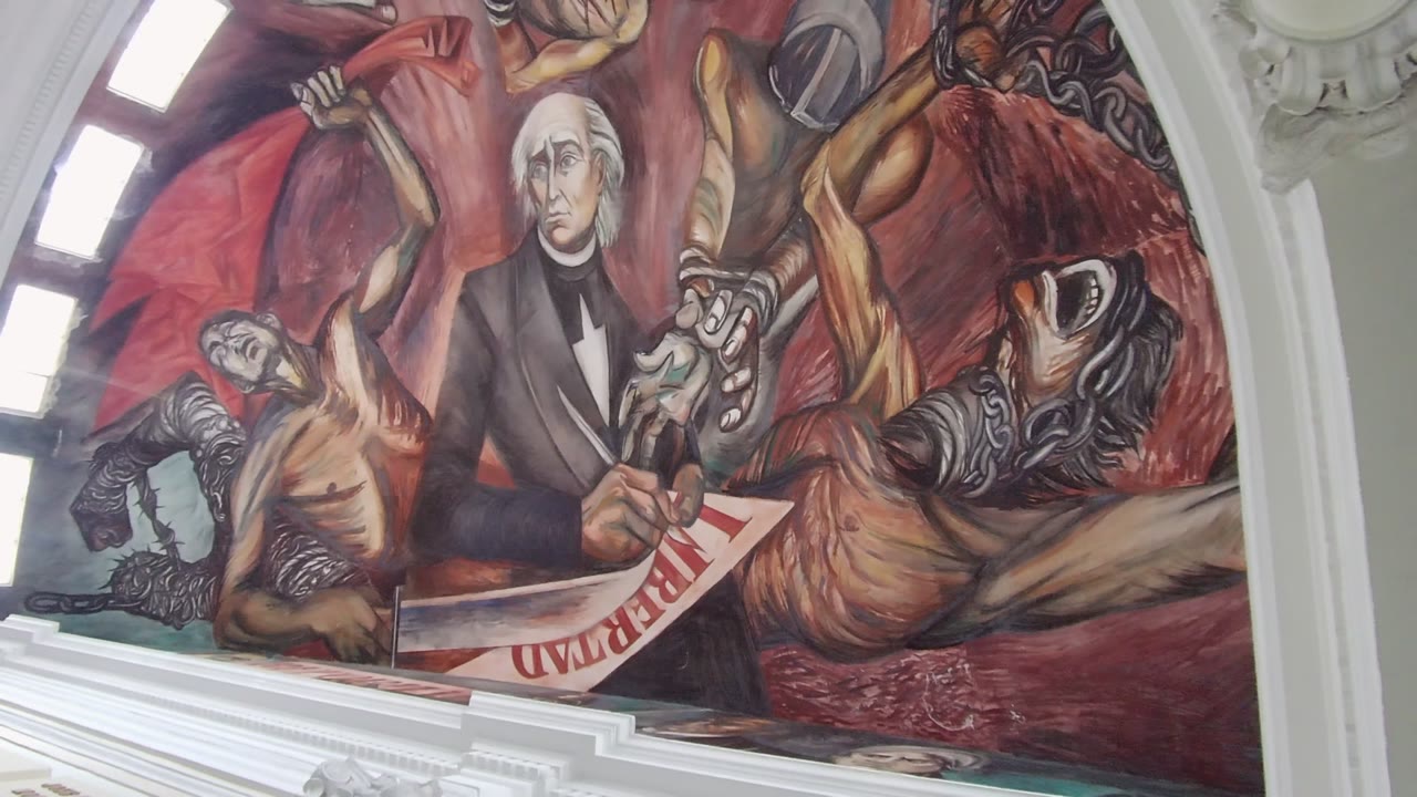 Close mural view with a suited figure, Liberty document, and bright arched window panels.