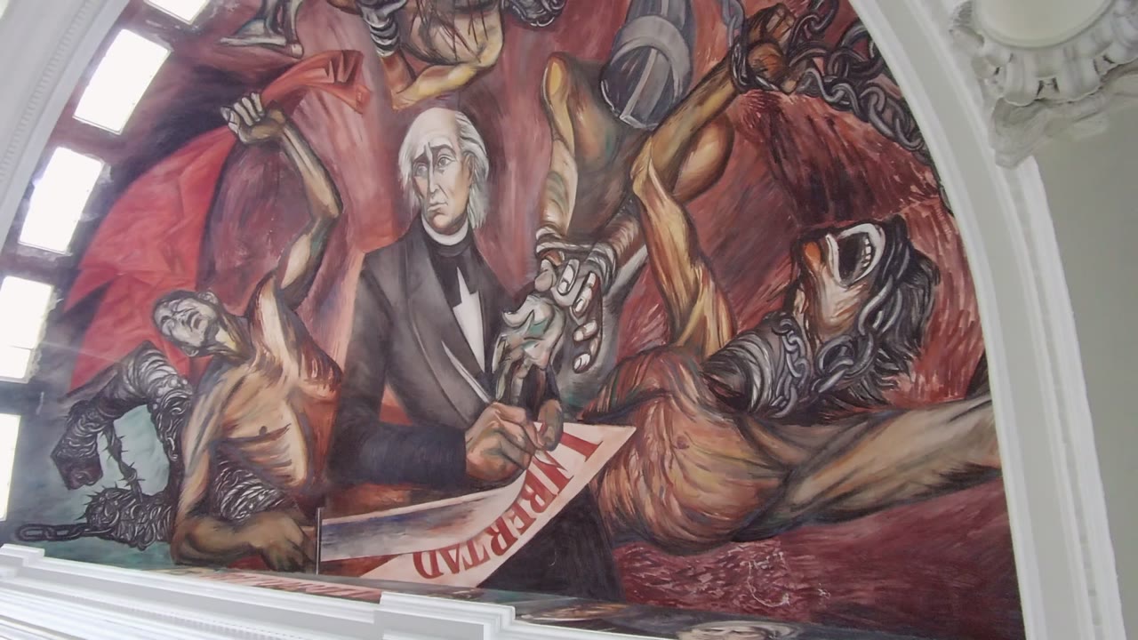 Guadalajara mural detail at 0:02 shows the Liberty document angled near a reclining painted figure, with the central historical figure and pale architectural arch visible, and no visible live people.