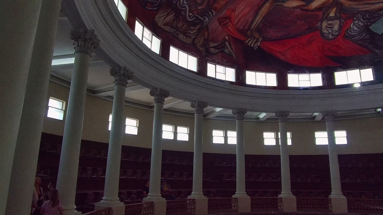Third frame shows the upward pan continuing inside the Guadalajara building, with foreground columns framing the circular balcony and more of the red-toned mural visible at the top.