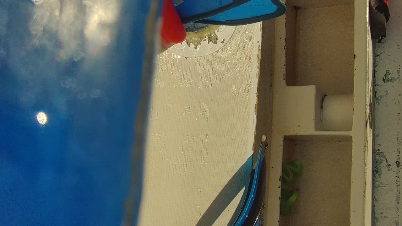 Tilted close frame from Cabo Pulmo showing a cream boat deck, blue water at the edge, and small gear details with no visible people.