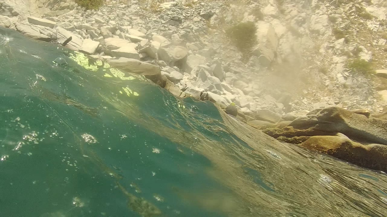 A brighter surface view shows clear turquoise water meeting a rocky Cabo Pulmo shoreline, with sunlit stones and no visible people.