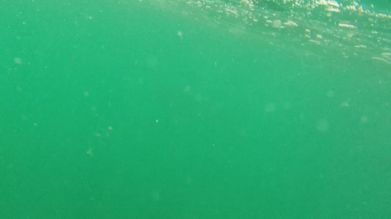 Underwater ocean surface with soft ripples and floating particles.
