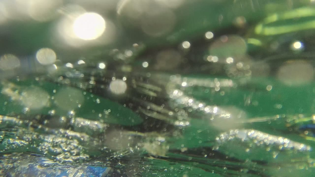 Soft-focus underwater surface with bubbles and bright reflected highlights.