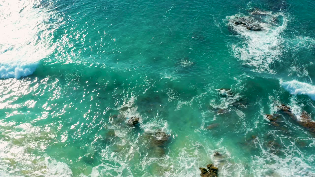 Wave line crossing clear water and rocks