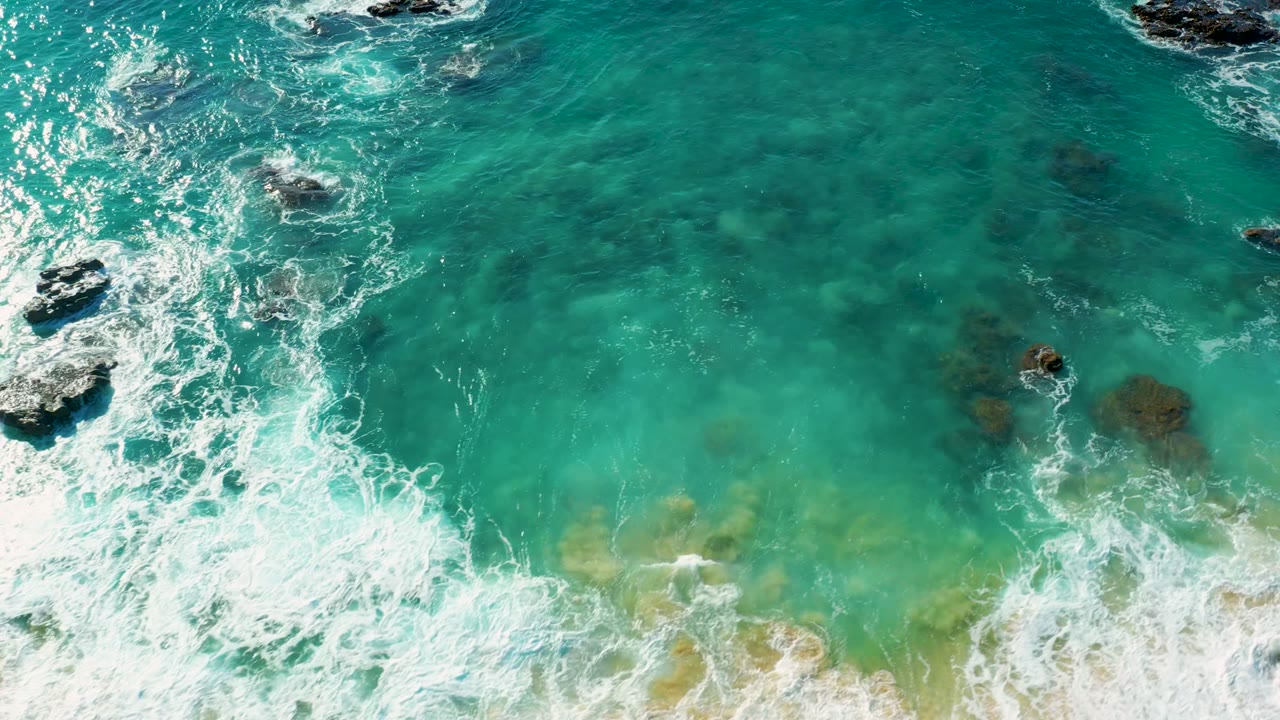 Overhead view of turquoise surf washing across submerged rocks at La Fortuna East Cape, Baja California Sur, with no visible people.