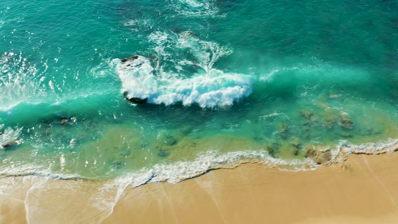 White wave line approaching sand through clear turquoise water