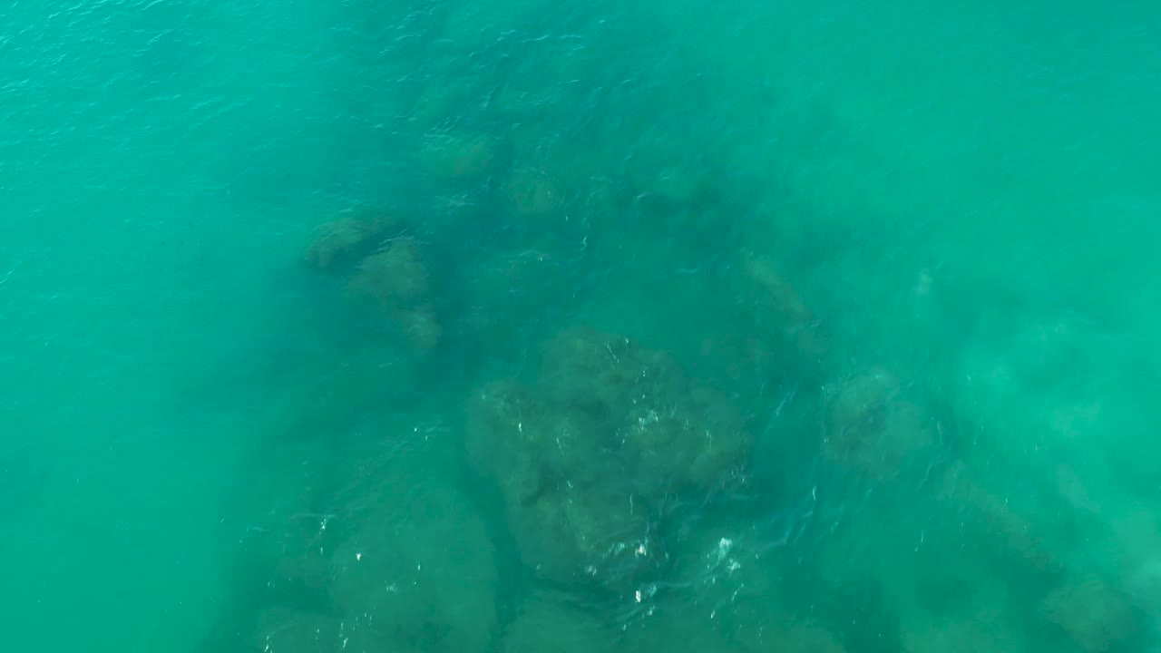 Overhead view of clear turquoise water above a broad submerged rock shape in La Fortuna, Baja California Sur, with no visible people.