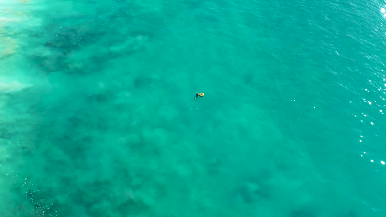 Small snorkeler floating in clear turquoise water with soft ripples.