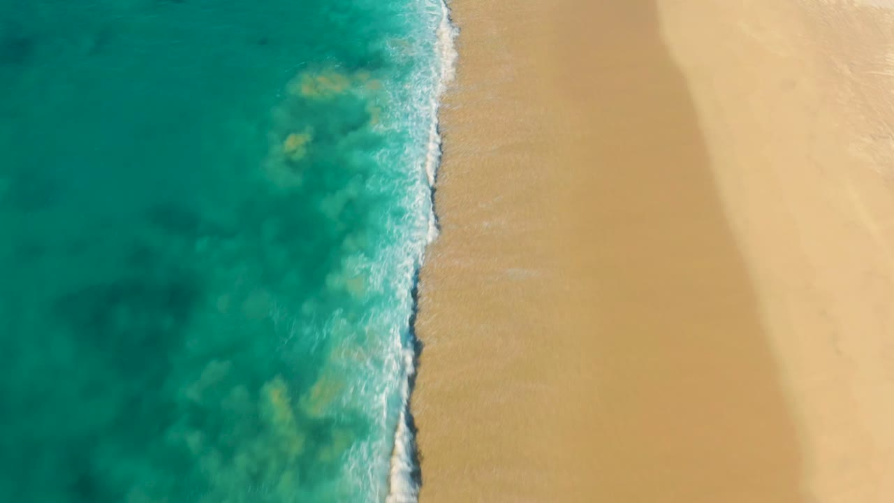 Top-down beach with surf foam and darker water patches