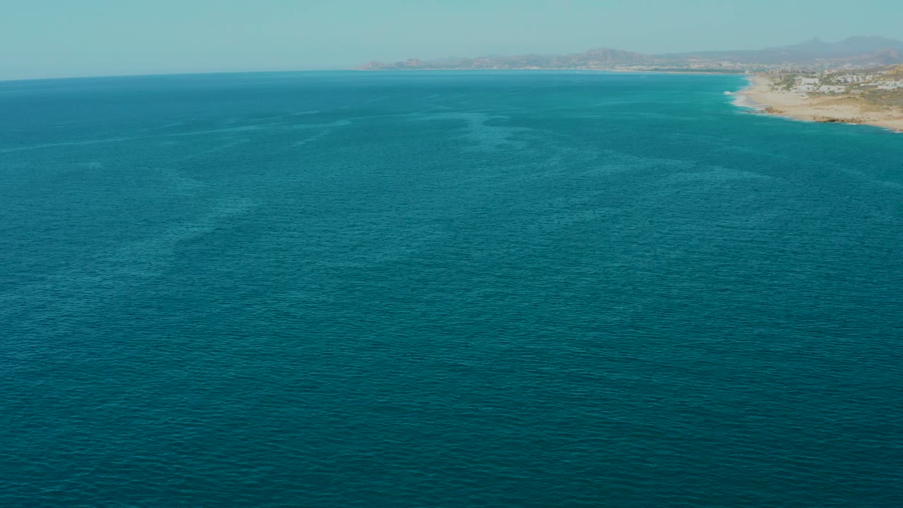 Wide ocean surface with coastline receding along the top right horizon
