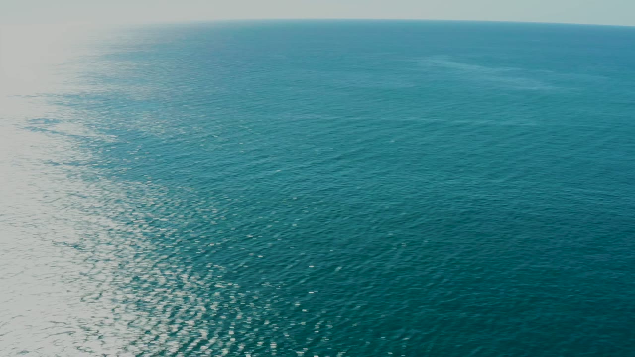 Sunlit ocean surface with shimmer on the left and blue water to the right.
