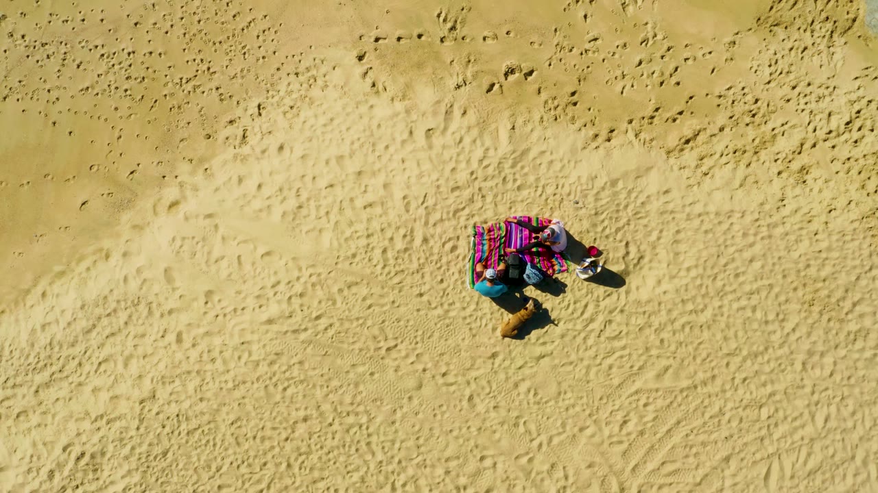 At two seconds, the overhead La Fortuna view shows the person still on the colorful towel, with the towel and shadow standing out against raked and marked sand.