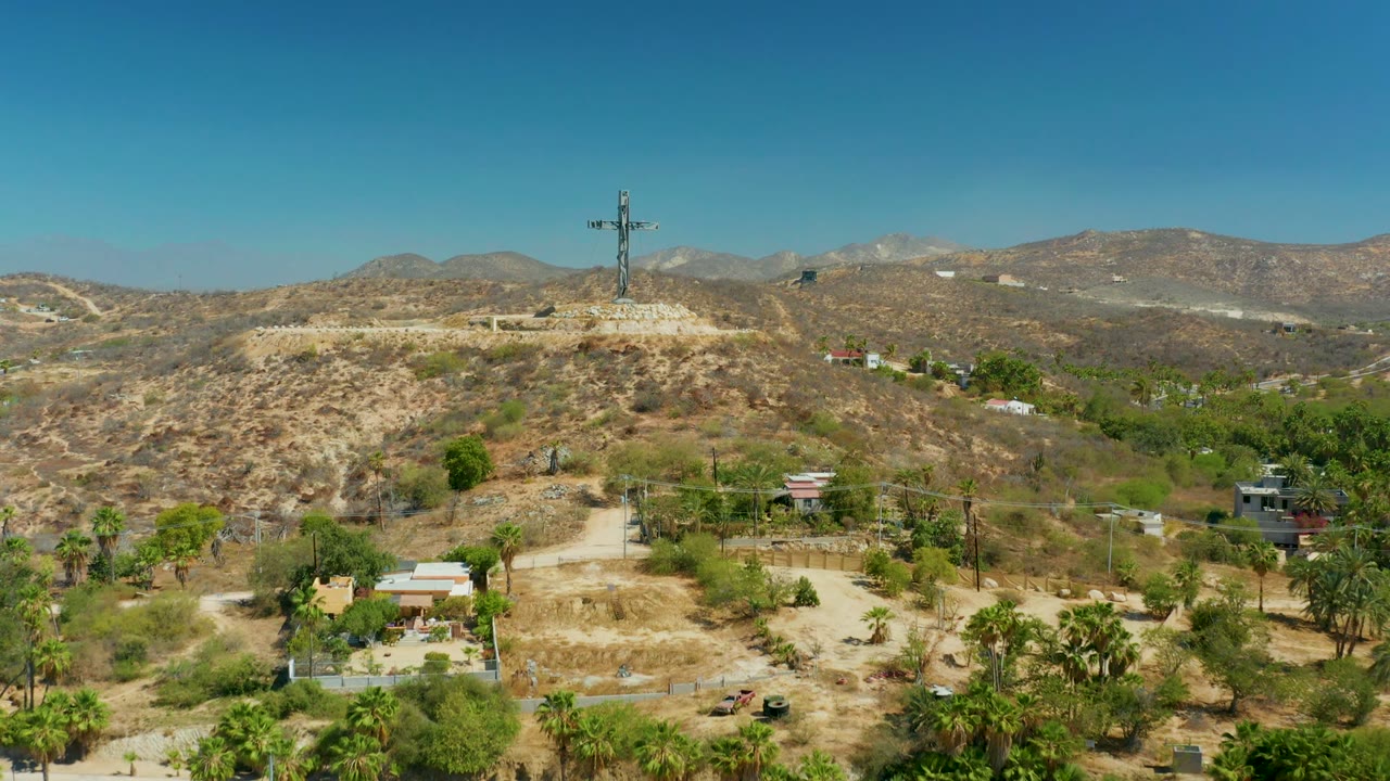Aerial view of cross on arid ridge with mountains behind