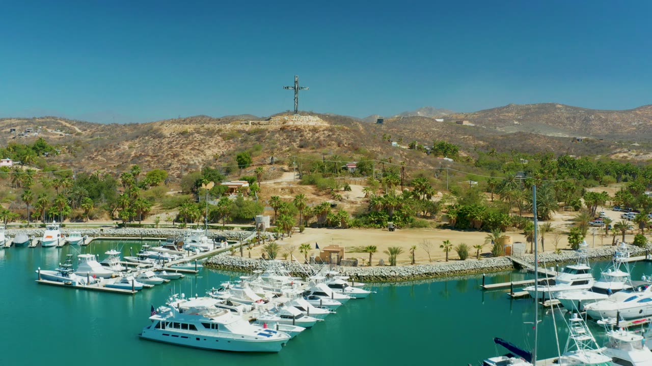 Wide aerial view over docked boats with the marina shore and dry hills beyond.