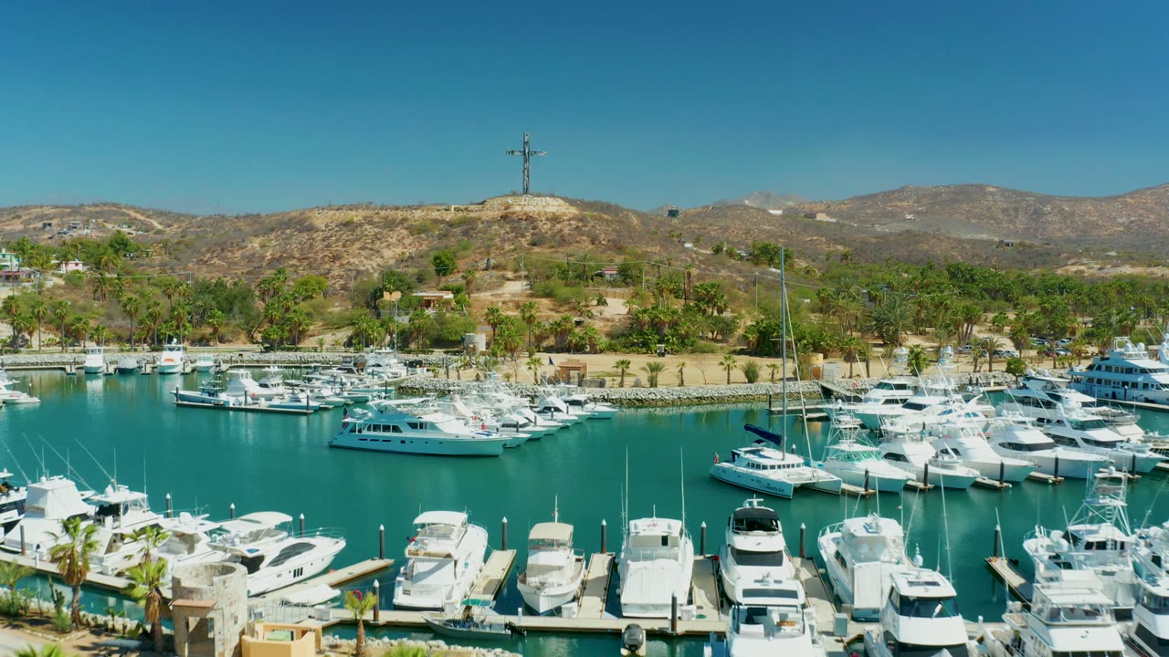 Docked boats and turquoise marina water with hills behind