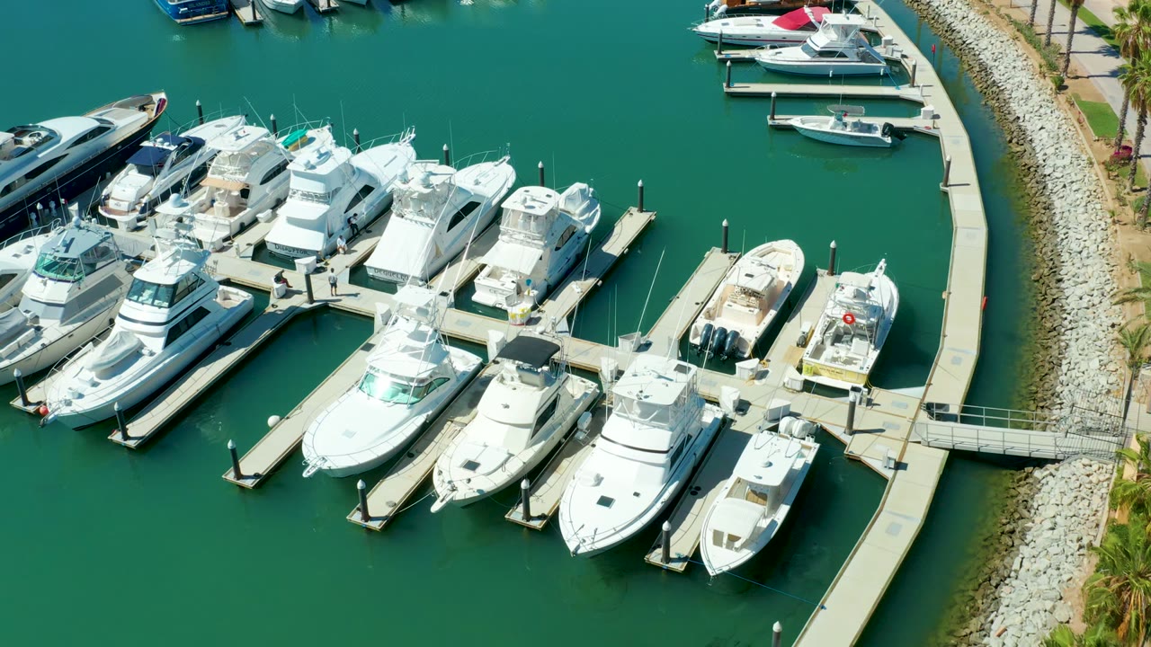 Aerial view of docked boats with curved walkway and rocky shore.
