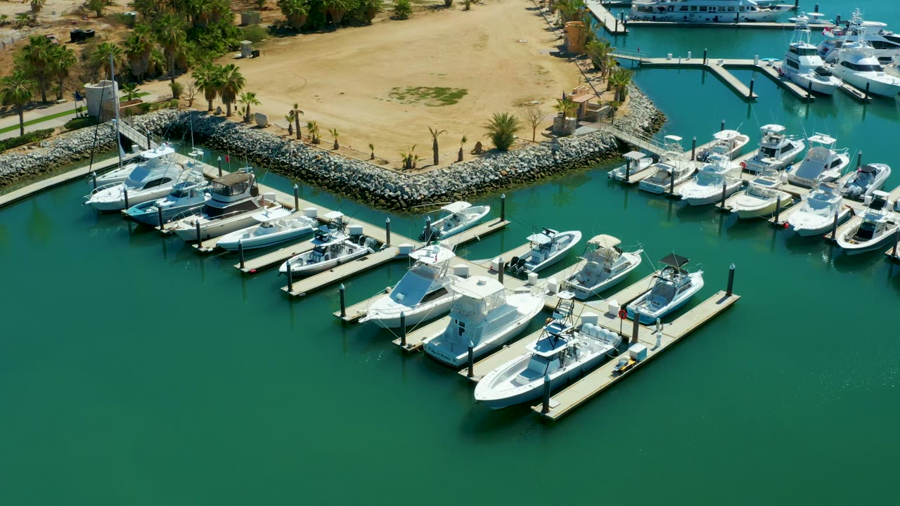 Docked marina boats seen from above with rippled green water and rocky shoreline.