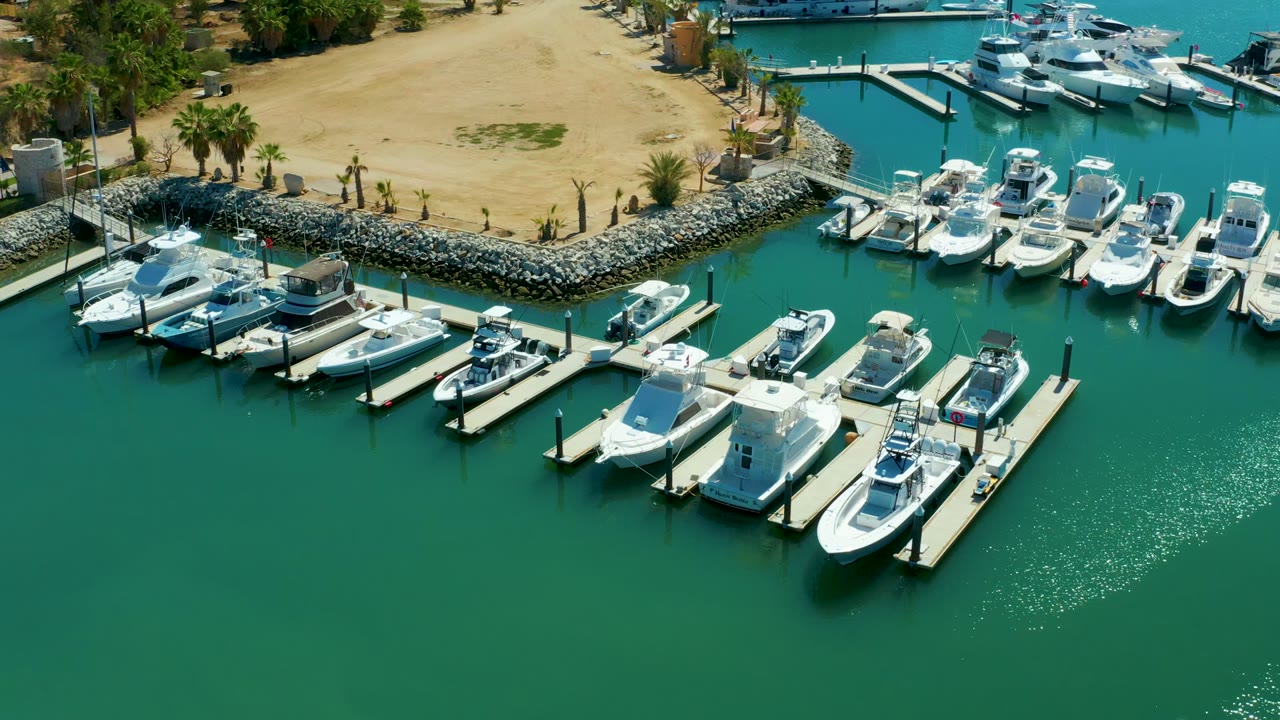 Aerial view of marina slips with white boats and rippled green-blue water.