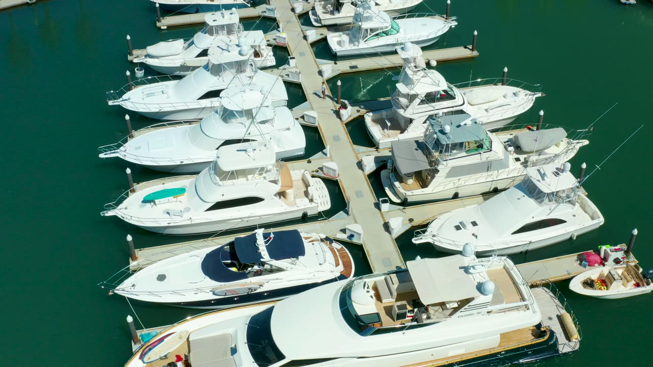 Aerial frame of Puerto Los Cabos marina with the small open boat closer to the right side of the dock and no visible people.