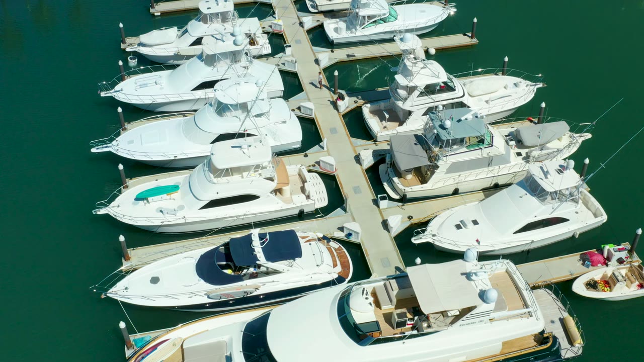 Top-down view of Puerto Los Cabos marina showing repeated yacht slips, white hulls, and green water with no visible people.