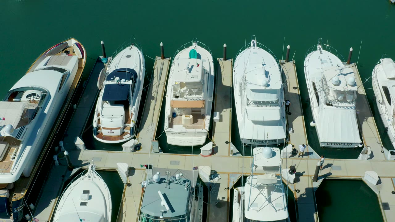 Top-down marina dock with several white yachts in slips