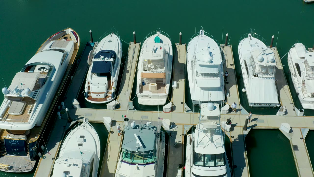 White yachts line both sides of a floating marina dock.